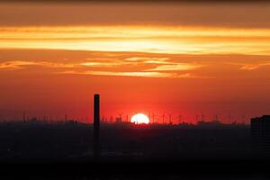 zon instelling over- de horizon in Rotterdam. rood licht bestraling van de wind boerderij en de haven. zonsondergang in Nederland foto