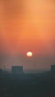 voorbijgaan vlak over- Amsterdam duiken in de zonne- schijf gedurende zonsondergang. op reis in modern keer. stad ondergedompeld in smog en een oranje lucht foto