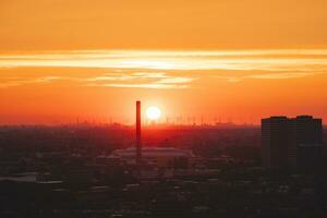 zon instelling over- de horizon in Rotterdam. rood licht bestraling van de wind boerderij en de haven. zonsondergang in Nederland foto