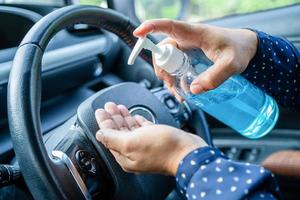 nieuwe normale, aziatische werkende vrouw die de hand wast door op blauwe alcoholdesinfecterende gel te drukken om de veiligheid te beschermen coronavirus in de auto foto