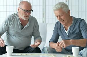 twee oud mannen zittend Bij tafel en spelen domino foto