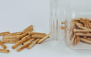 stapel van biscuit stokjes in een glas pot Aan een wit achtergrond foto