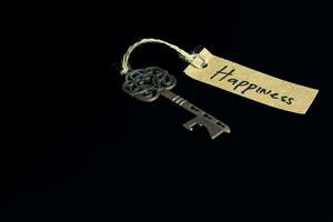 oud decoratief sleutel en handgeschreven label geluk gebonden met rietje touw Aan zwart achtergrond foto