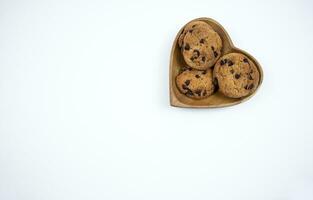 chocola spaander koekjes Aan een hart vormig bord Aan een wit achtergrond foto