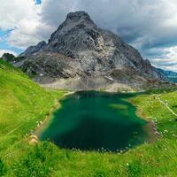 visie van volaia meer, Wolayersee, in de grens van Italië en Oostenrijk met coglians berg in de achtergrond. bewolkt dag met sommige zon opening. levendig kleuren. mooi bestemmingen voor wandelaars. foto