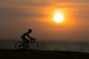 silhouetten fietsers Aan de strand Bij zonsondergang. foto