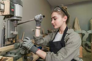 een jong vrouw timmerman werken project in haar werkplaats. vrouw timmerman maken houten meubilair. foto