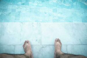 ontspannende Mens met zijn voeten Aan zwembad Bij zwemmen zwembad foto
