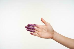 binnen- foto van verheven jong vrouw hand- tonen palm terwijl poseren over- wit achtergrond, hebben Purper sparkles Aan het, gaan naar schudden van iemand hand-