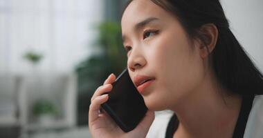 portret van jong Aziatisch vrouw glimlachen zelfverzekerd pratend Aan de smartphone in leven kamer Bij thuis, bellen telefoon foto