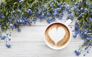 vergeet-mij-nietje bloemen en kopje koffie op een houten achtergrond