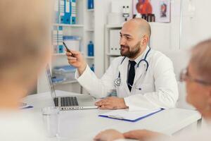 arts Mens uitleggen ziekte medisch expertise naar ziekenhuis team bespreken pillen geneesmiddel behandeling werken in wetenschap vergadering kamer. specialist dokter zittend Bij bureau in kliniek kantoor foto