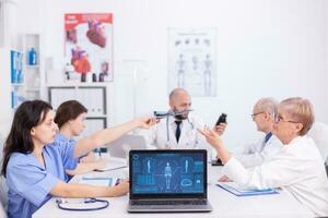 groep van medisch personeel bespreken in ziekenhuis vergadering kamer over geduldig radiografie. kliniek deskundige therapeut pratend met collega's over ziekte, geneeskunde professioneel foto