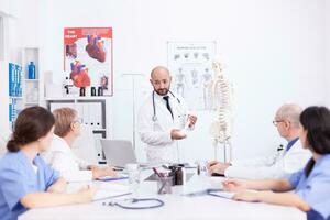 dokter maken presentatie naar medisch personeel in ziekenhuis radiologie Oppervlakte. kliniek deskundige therapeut pratend met collega's over ziekte, geneeskunde professioneel foto