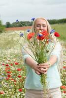 mooi middelbare leeftijd blond vrouw staat tussen een bloeiend veld- van klaprozen foto