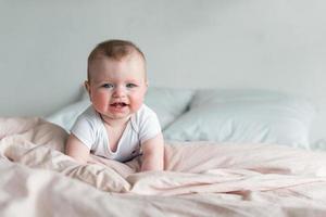 schattige, mooie kleine baby liggend op zijn buik in bed met roze lingerie foto