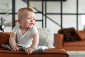 mooi, schattig, klein meisje dat op de bank staat, verheugt zich oprecht foto