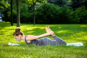 jong vrouw aan het doen yoga opdrachten in de zomer stad park. foto