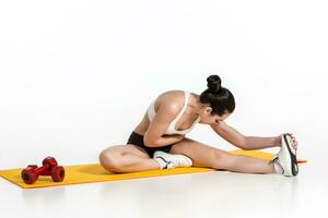 aantrekkelijk vrouw aan het doen opdrachten. brunette fit lichaam Aan yoga mat foto