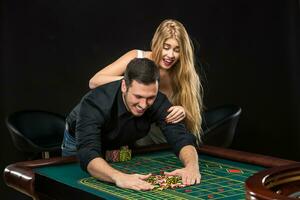 jong paar vieren winnen Bij roulette tafel in casino. foto