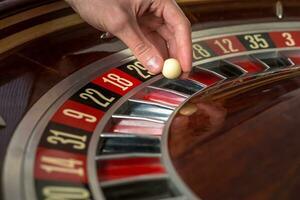 roulette wiel en croupier hand- met wit bal in casino foto