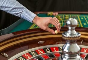 roulette wiel en croupier hand- met wit bal in casino foto