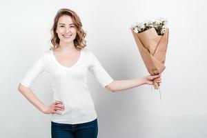 schattig kortharig meisje in een wit leeg t-shirt met een boeket kleurrijke bloemen, glimlachend in het algemeen over een witte achtergrond. foto