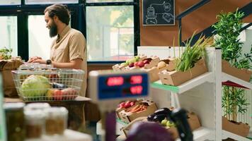 Mens Bij nul verspilling supermarkt zoeken voor gezond voedsel en bijkeuken benodigdheden, genieten van boodschappen doen Bij lokaal biologisch kruidenier op te slaan. cliënt in eco vriendelijk winkel op zoek voor vers fruit en groenten. foto