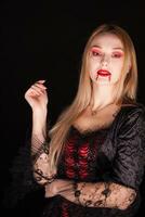 vampier mooi vrouw met bloederig lippen over- zwart achtergrond. halloween kostuum. foto
