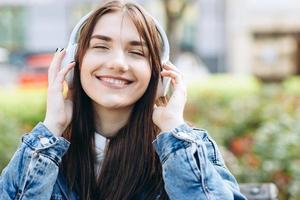 mooi meisje met gesloten ogen in koptelefoon, oprecht glimlachend, genietend van je favoriete muziek foto