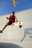 jong skateboarder springt omhoog met zijn bord in voorkant van een metaal achtergrond foto