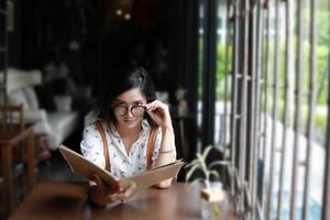 aziatische vrouw open menu om te bestellen in koffiecafé en restaurant en glimlachen voor een gelukkige tijd foto