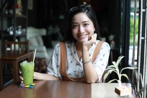 Aziatische vrouwen glimlachend en gelukkig ontspannend en houdend theekopje in een coffeeshop foto