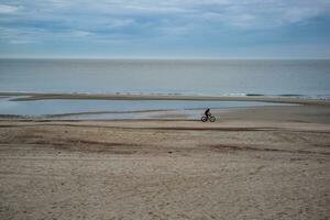 duinen, wolken, golfbreker Bij eb tij Aan zanderig strand foto