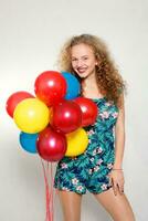 tiener- meisje met helium ballonnen over- grijs achtergrond foto