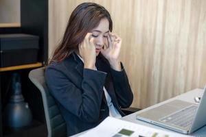Aziatische zakenvrouw serieus over het harde werk tot de hoofdpijn