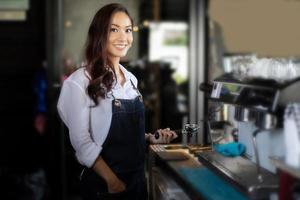 aziatische vrouwenbarista glimlacht en gebruikt koffiemachine in coffeeshopteller - werkende vrouw, eigenaar van een klein bedrijf, eten en drinken caféconcept foto