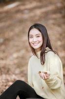 mooie aziatische vrouw die een gelukkig meisje glimlacht en warme kleding winter- en herfstportret draagt in de buitenlucht in het park foto