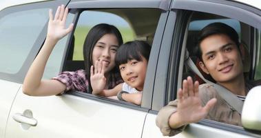 gelukkig klein meisje met aziatische familie die in de auto zit om te genieten van een roadtrip en zomervakantie in een camper foto