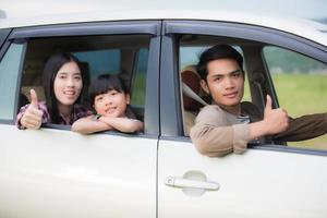 gelukkig klein meisje met aziatische familie die in de auto zit om te genieten van een roadtrip en zomervakantie in een camper foto