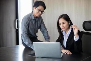 Aziatische zakenlieden en groep die notebook gebruiken voor zakenpartners die documenten en ideeën bespreken tijdens vergaderingen en zakenvrouwen die blij glimlachen om te werken foto