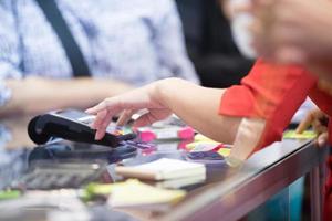 Aziatische zakenvrouwen hand met creditcard veegmachine voor betaling in cafetaria en supermarkt foto