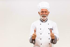portret van senior chef tonen duim omhoog Aan grijs achtergrond. foto
