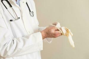 beeld van mannetje dokter zetten Aan beschermend handschoenen. foto