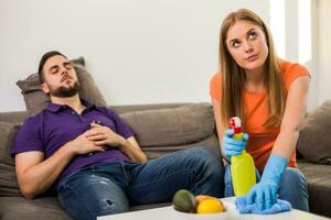 boos vrouw en man zijn hebben conflict omdat man is nooit helpen zijn vrouw met schoonmaak huis. foto