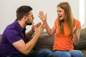 boos vrouw en man zijn hebben conflict terwijl ze zittend Aan sofa Bij hun huis. foto