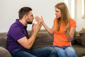 boos vrouw en man zijn hebben conflict terwijl ze zittend Aan sofa Bij hun huis. foto