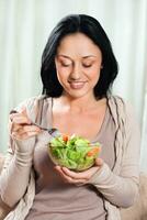 jonge vrouw salade eten foto