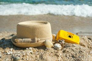 hoed en camera Aan de strand met een achtergrond zee golven foto
