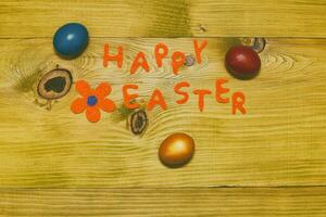 gelukkig Pasen bericht met geschilderd eieren en bloem Aan houten tafel.afgezwakt foto. foto